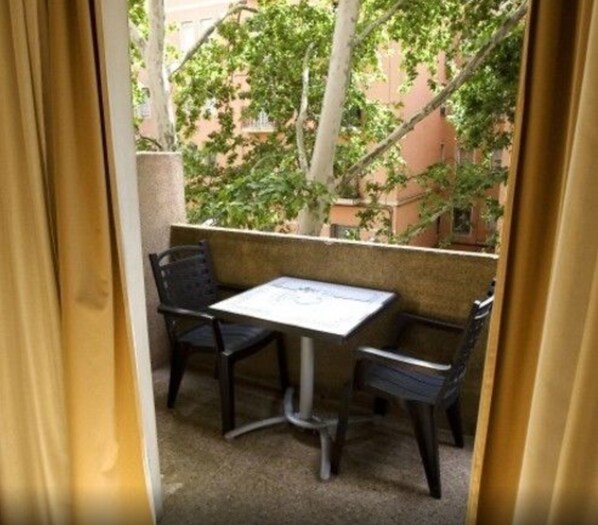 A small outdoor seating area with a table and two chairs, surrounded by a low wall and greenery. - Hotel Vernisa Xativa (Xàtiva)