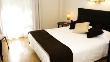 A hotel room with a bed, a nightstand, a lamp, and an air conditioning unit.