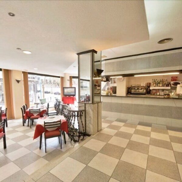 A restaurant with a checkered floor, tables with red tablecloths, and a bar area with bottles. - Hotel Vernisa Xativa (Xàtiva)