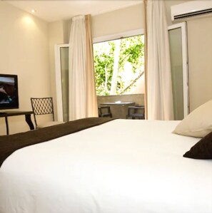 A bedroom with a bed, a TV, a desk, and a window with curtains. - Hotel Vernisa Xativa (Xàtiva)