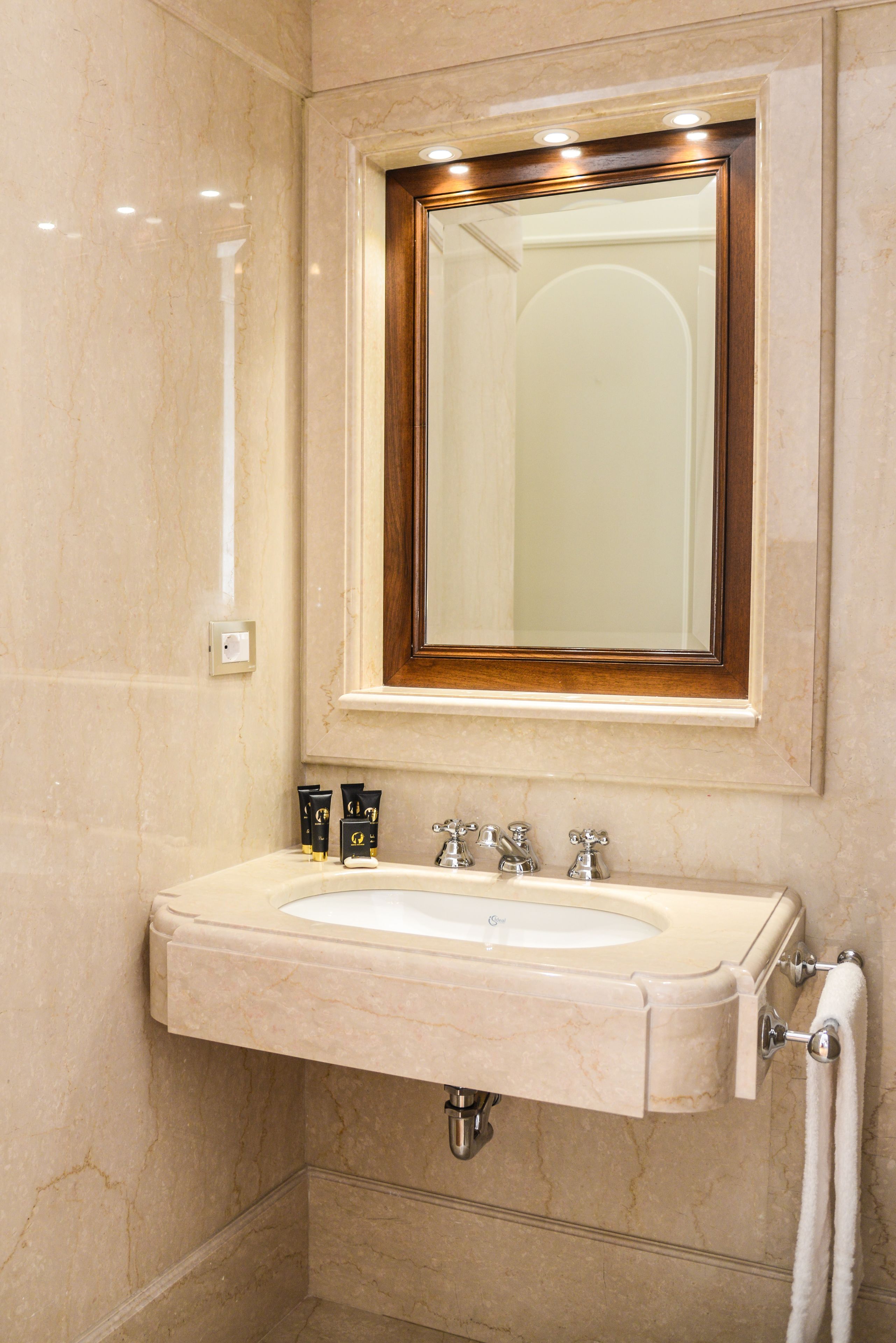A bathroom with a marble sink, a mirror with a wooden frame, and a towel rack.