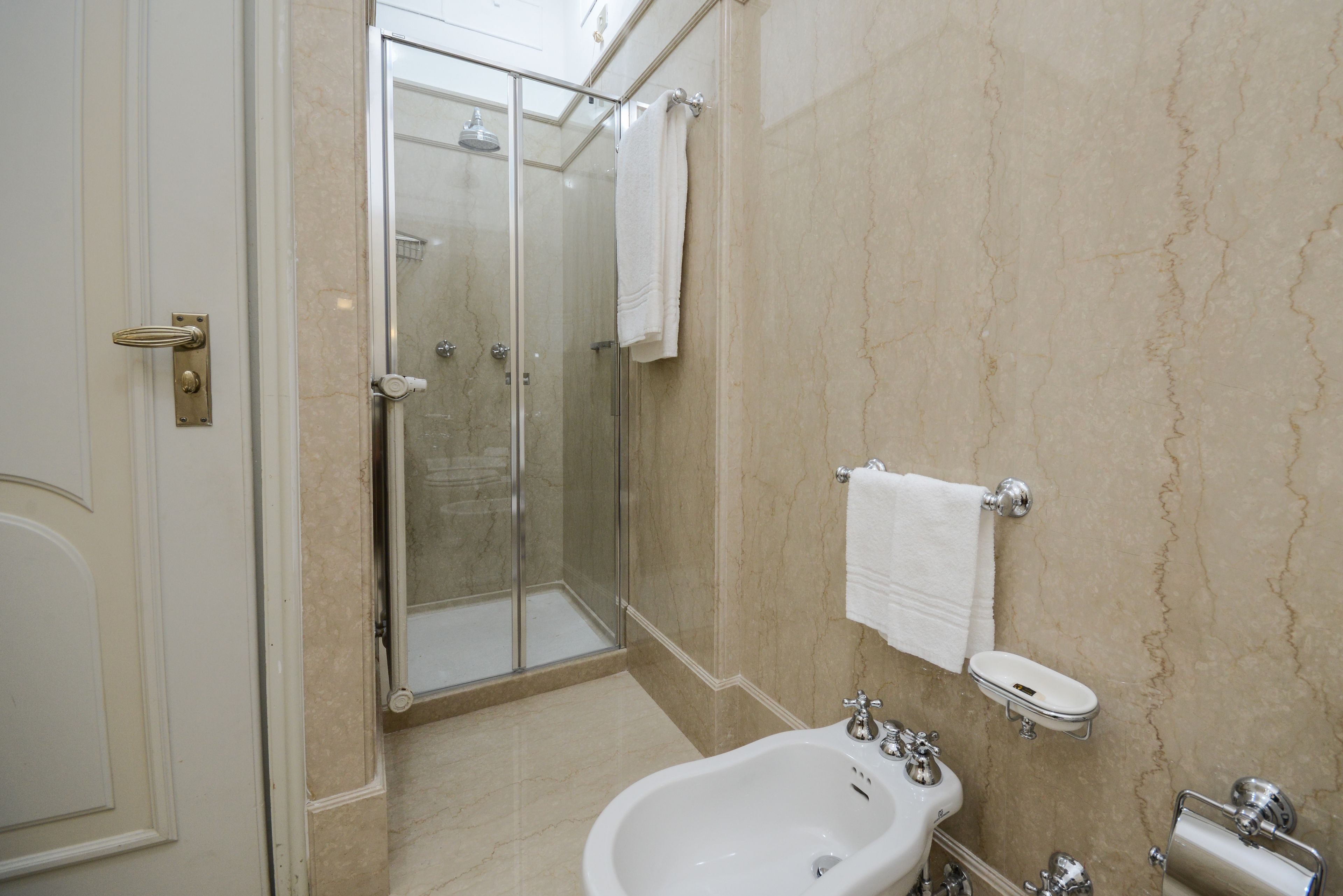 A bathroom with a glass-enclosed shower, a bathtub, and a toilet.
