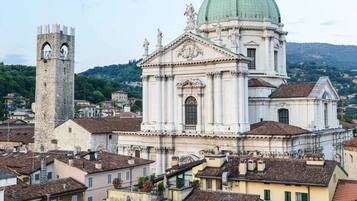 Un edificio storico con una torre imponente e una grande cupola, circondato da edifici tradizionali dai tetti in tegole rosse.