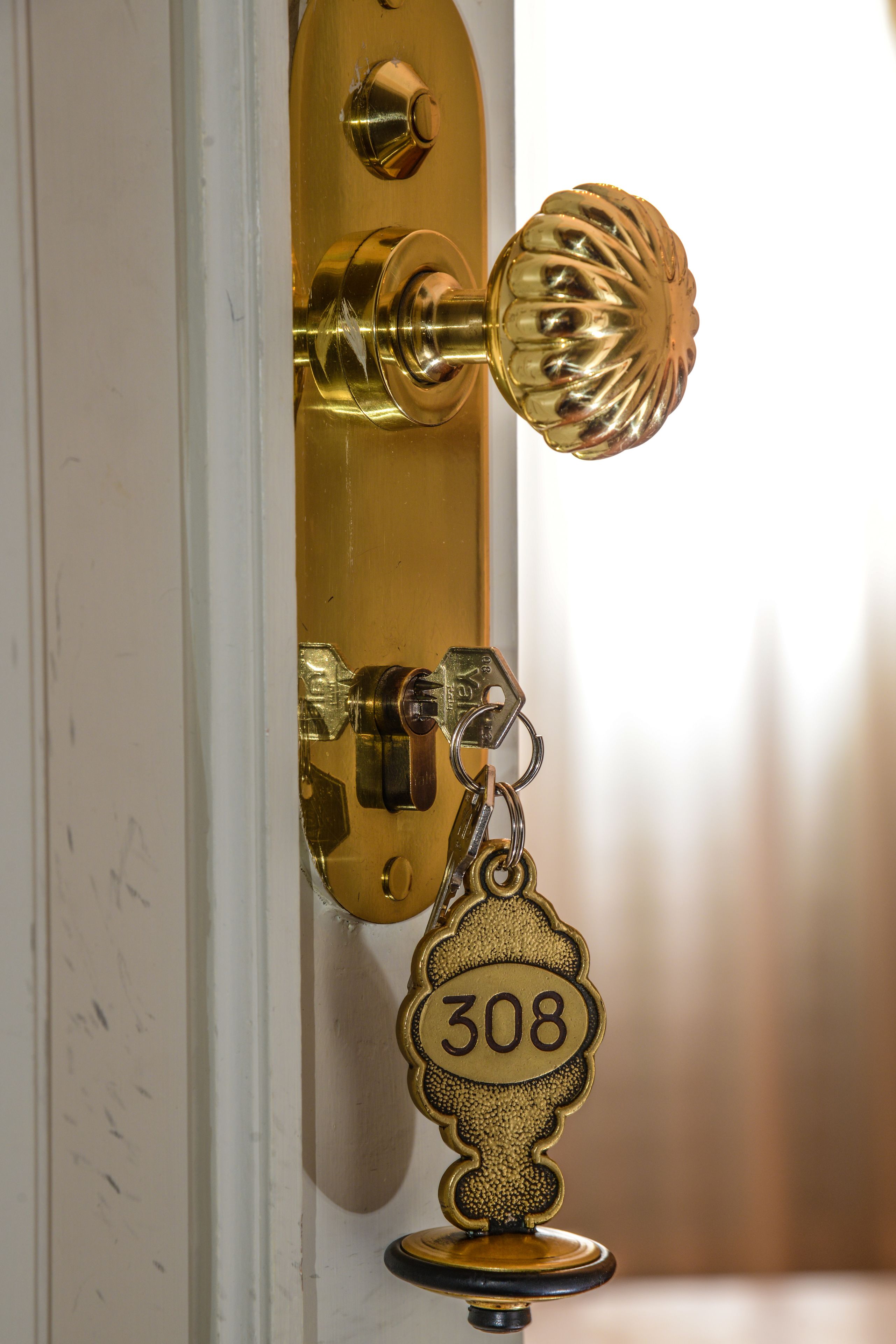 Eine Messing-Türgriff mit Schlüsselloch und ein Schlüsselbund mit der Nummer ‚308‘.