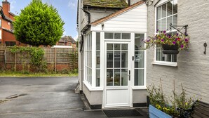 A white building with a door marked "Entrance" and a sign above it reading "Please Ring the Bell."