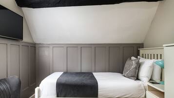 A bedroom with a bed, a chair, and a nightstand.