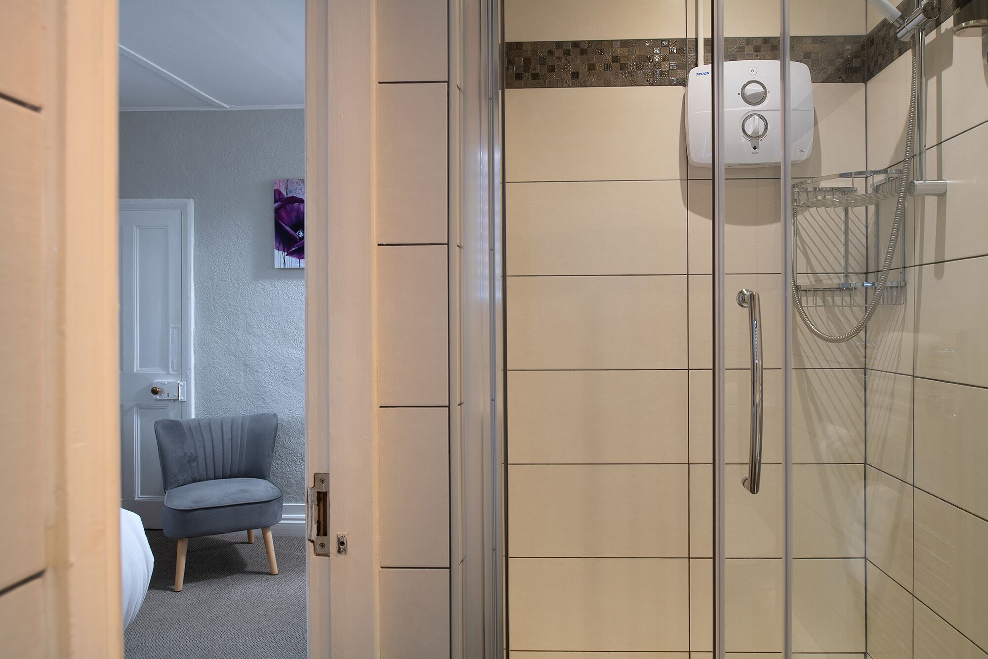 Un baño con cabina de ducha de vidrio, un perchero para toallas y un dispensador de jabón de pared.