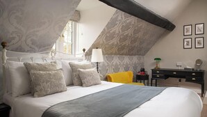 A bedroom with a bed, a nightstand, a desk, a chair, and a window.