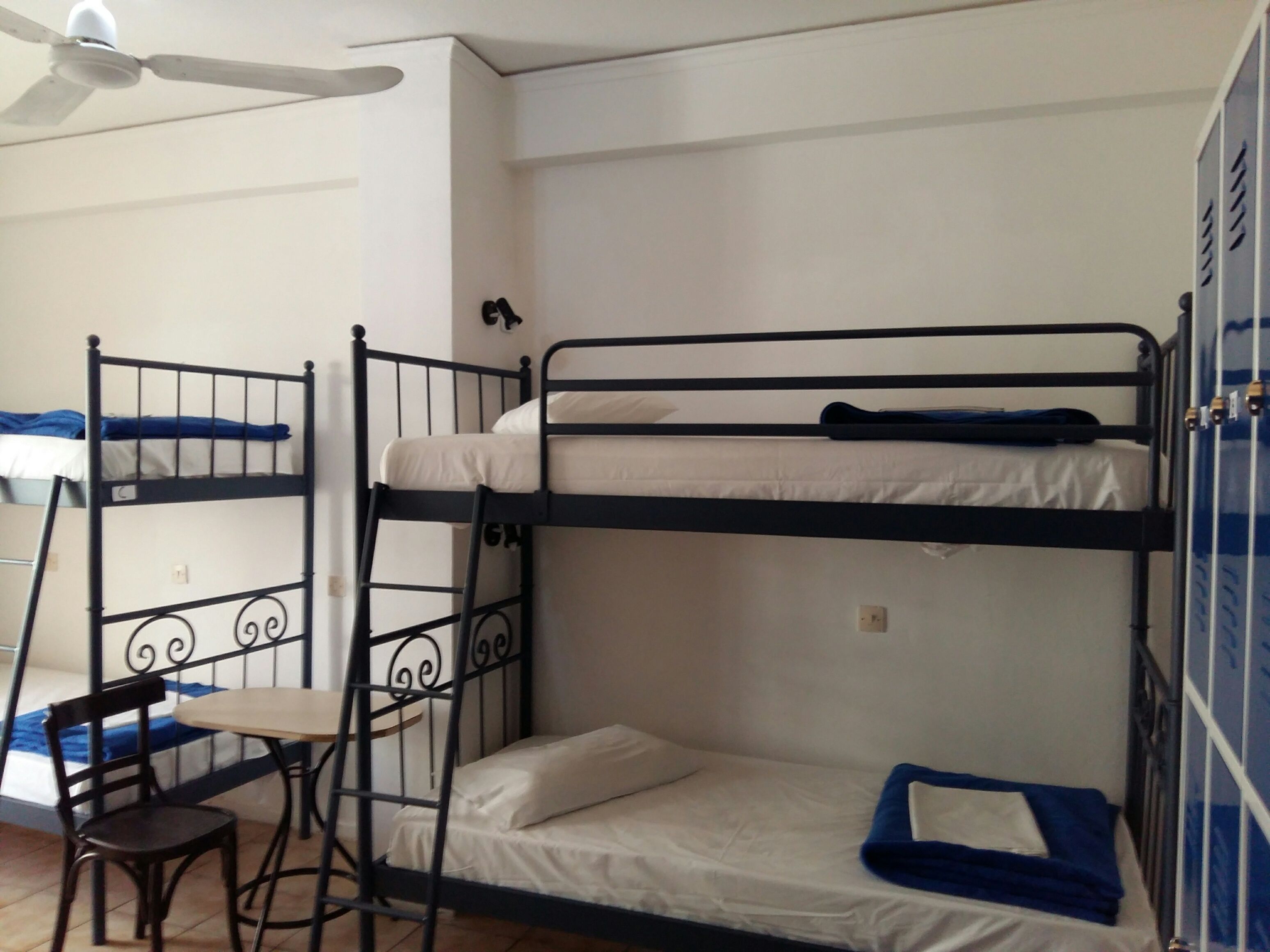 A bunk bed room with a desk and chair, a ceiling fan, and a wardrobe.