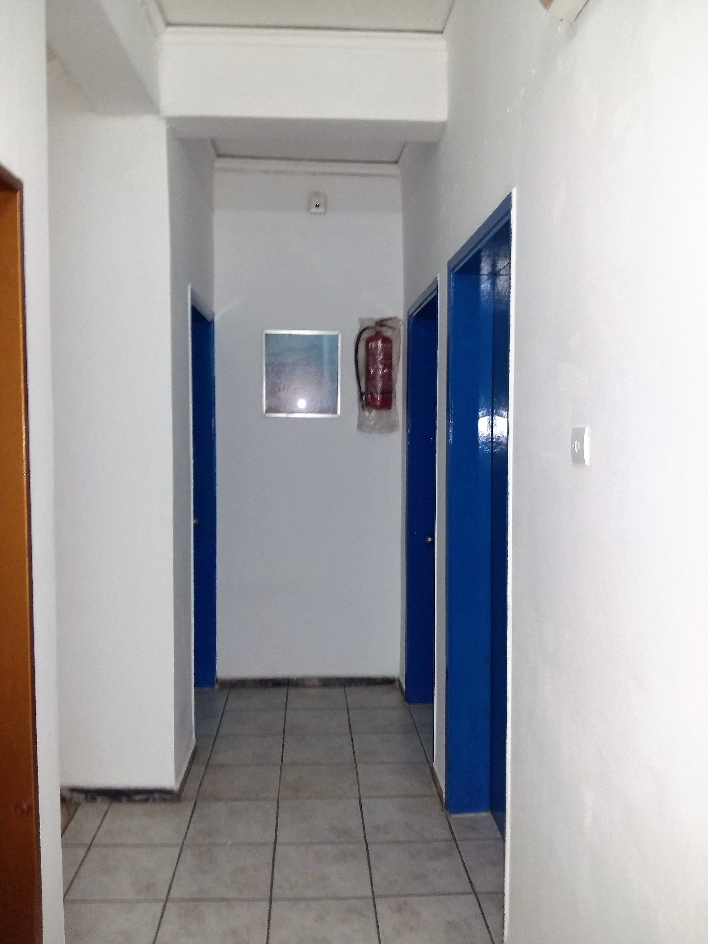 A hallway with blue doors, a fire extinguisher, and a small window.