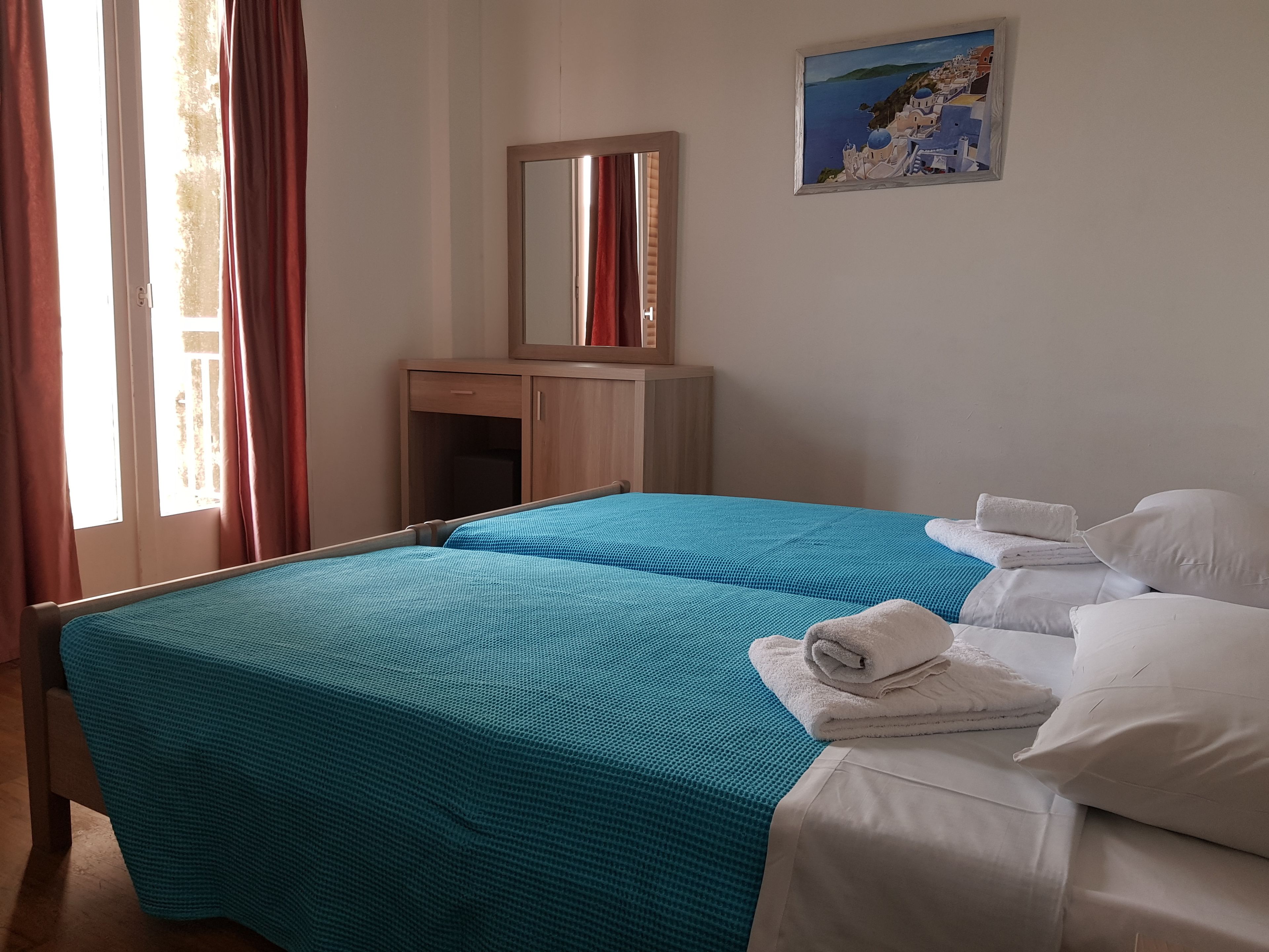 A hotel room with a bed, a nightstand, a mirror, and a painting on the wall.