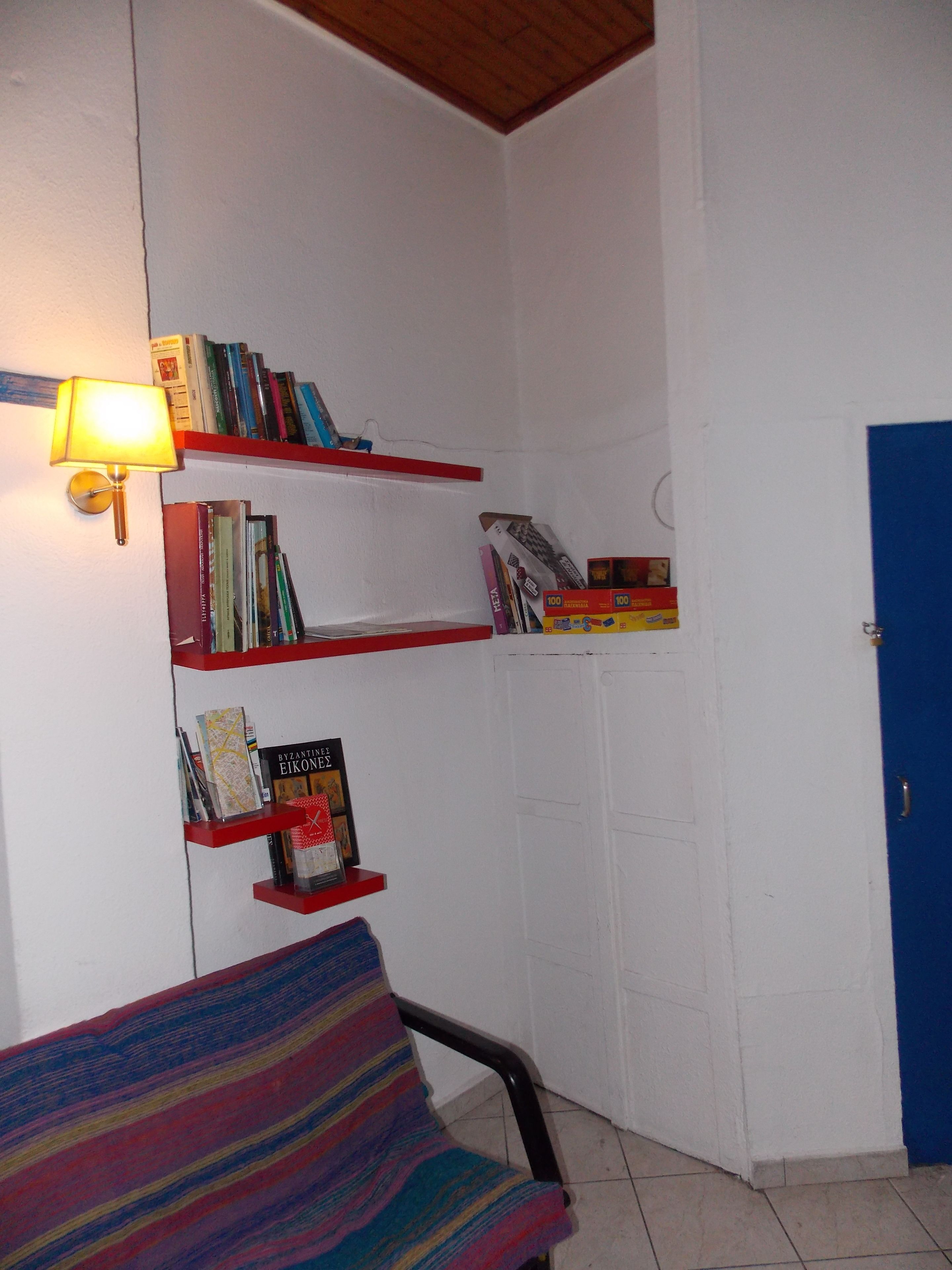 A room with a bookshelf, a lamp, a door, and a chair.