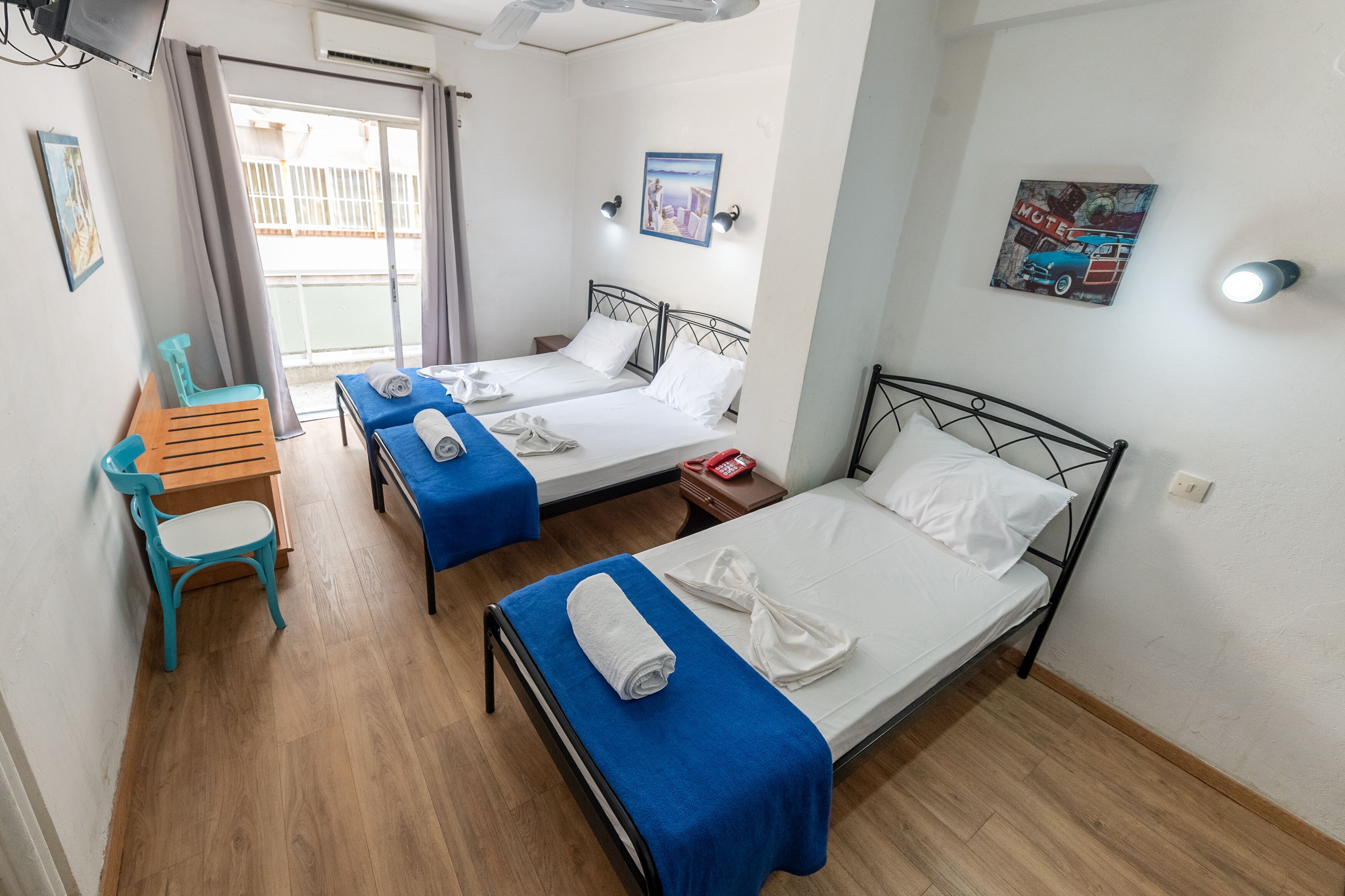 Une chambre d’hôtel avec deux lits, un bureau, une chaise et une fenêtre donnant sur un paysage agréable.
