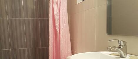 A bathroom with a white sink, a mirror, and a shower curtain.