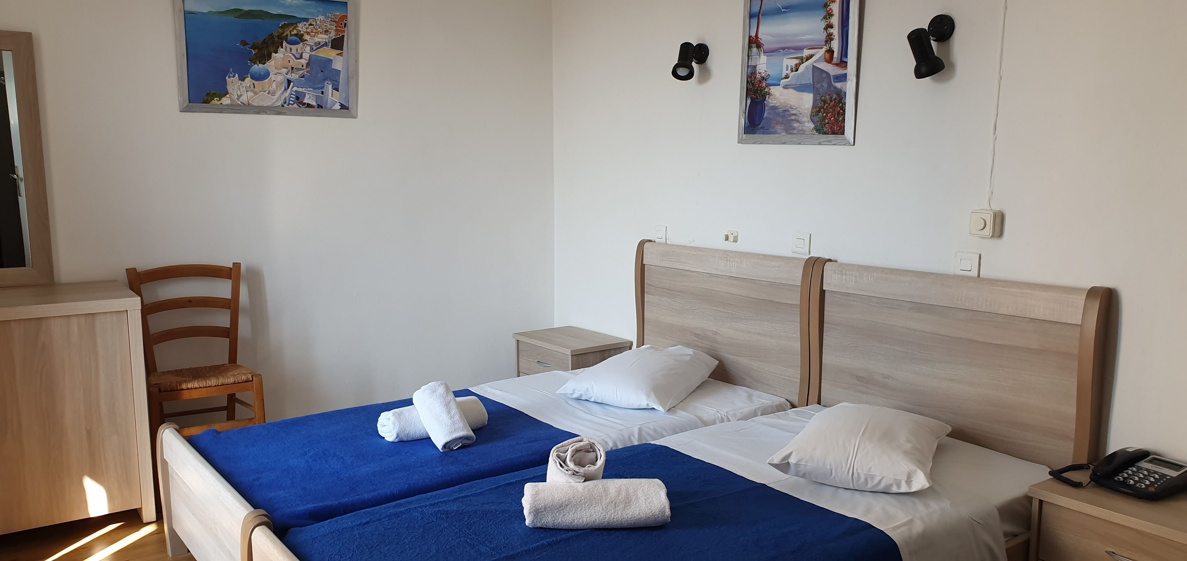 A hotel room with two beds, a wooden headboard, a desk, and a chair.