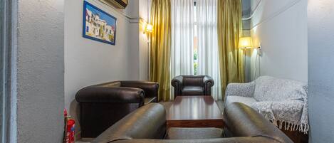 A room with a wooden ceiling, a table with leather chairs, a sofa, and a fire extinguisher.