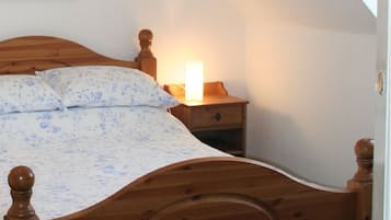 A bedroom with a wooden bed, a bedside table with a lamp, and a nightstand.