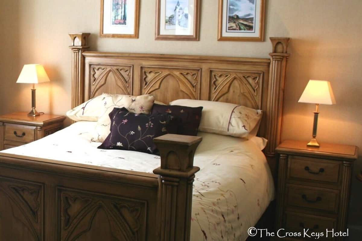 A bedroom with a wooden bed, two bedside tables with lamps, and three framed pictures on the wall.