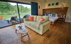 A cozy living room with a sofa, a small table, and a bed with a wooden headboard. - The Baron at Bucknell (Bucknell)