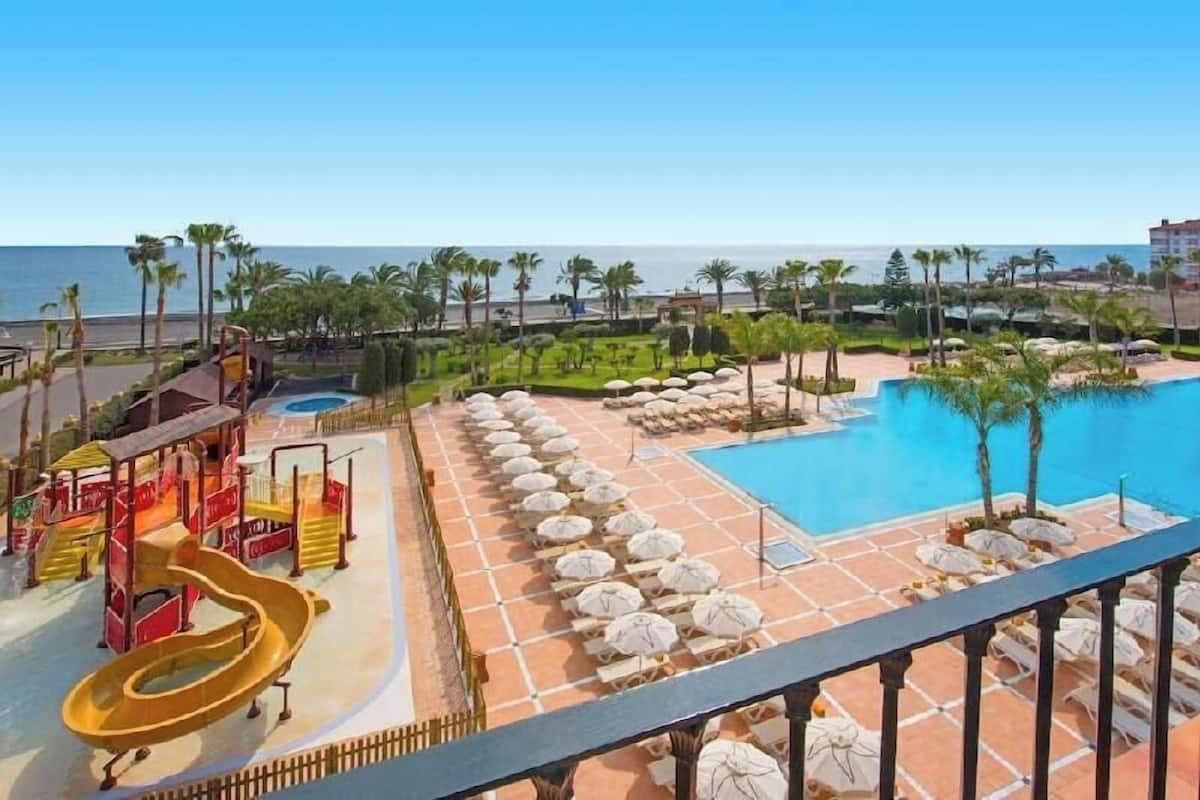 Área de piscina do resort com um toboágua, espreguiçadeiras e vista para o oceano.