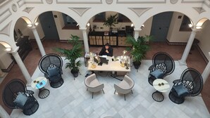 Un amplio patio interior con una mesa central, rodeado de sillas y plantas en macetas.