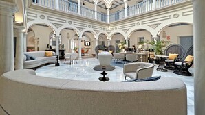 Un amplio atrio con techos altos, varias zonas de estar y un espacio central abierto.