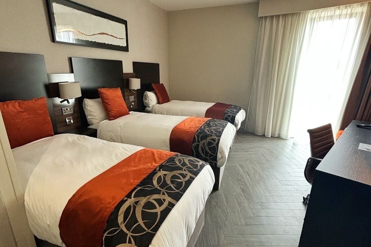 A hotel room with two beds, a desk, and a chair.