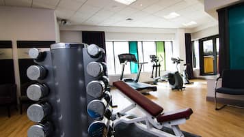A gym with a bench press, weight stacks, and cardio equipment.