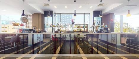 A modern bar area with a glass railing, bar counter, and various bottles and glasses.