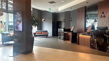 A modern lobby with a reception desk, seating area, and large windows.