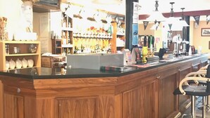A bar area with a wooden counter, bar stools, and a variety of bottles and glasses on shelves. - The Anchor Inn (March)