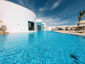 Una piscina al aire libre, sombrillas, tumbonas