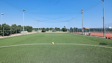 Un campo deportivo con un arco, rodeado de vallas y farolas.