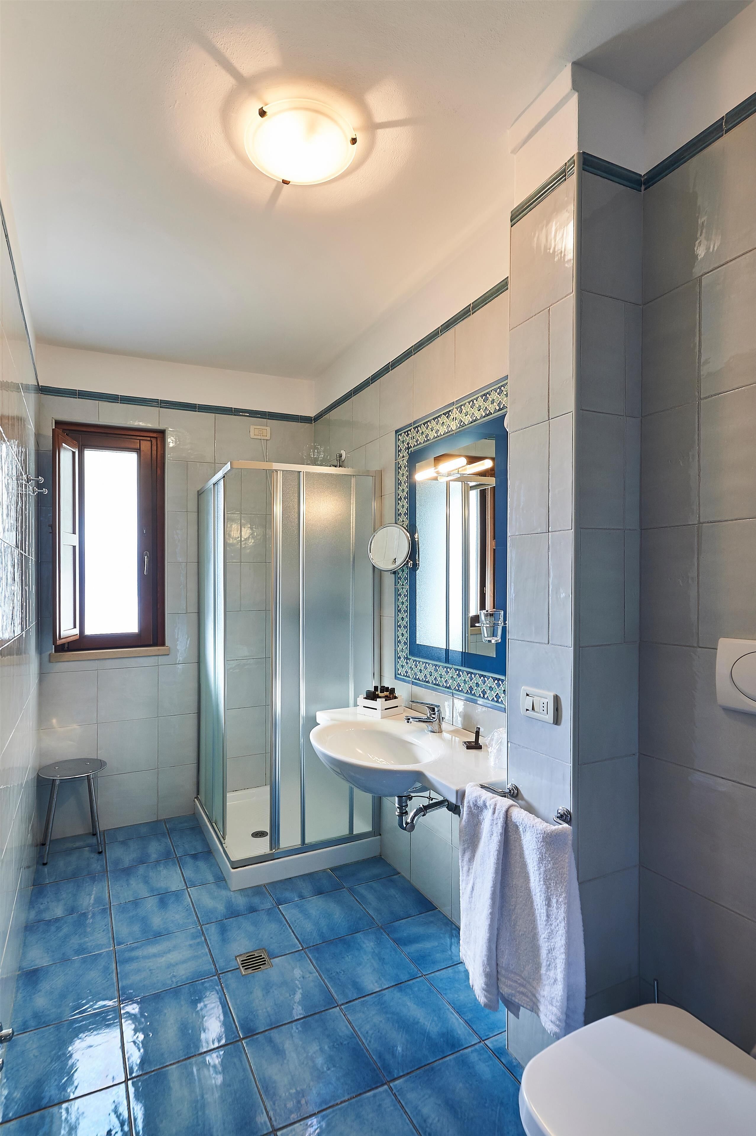 A bathroom with a glass shower enclosure, a sink with a mirror, and a toilet.