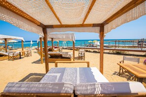 Een privéstrand, ligstoelen aan het strand, parasols