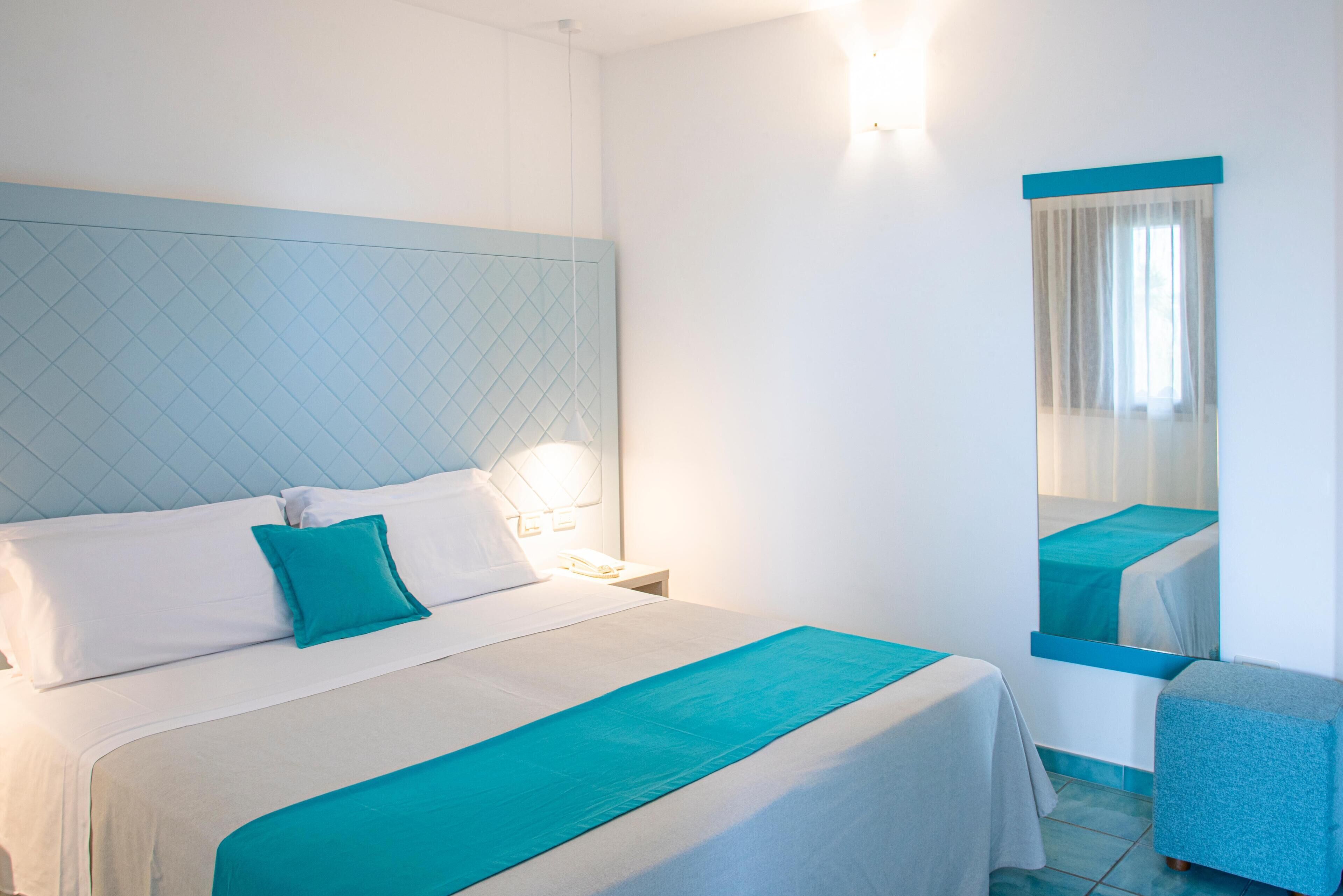 Ein Hotelzimmer mit einem großen Bett, einem Nachttisch, einem Spiegel und einer kleinen Sitzecke.