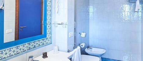 Un baño con suelo de azulejos azules, un lavabo blanco, un inodoro y un espejo con marco azul.