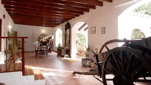 Una habitación amplia con techo de madera, un comedor con sillas y una mesa, y un carrito grande de madera.