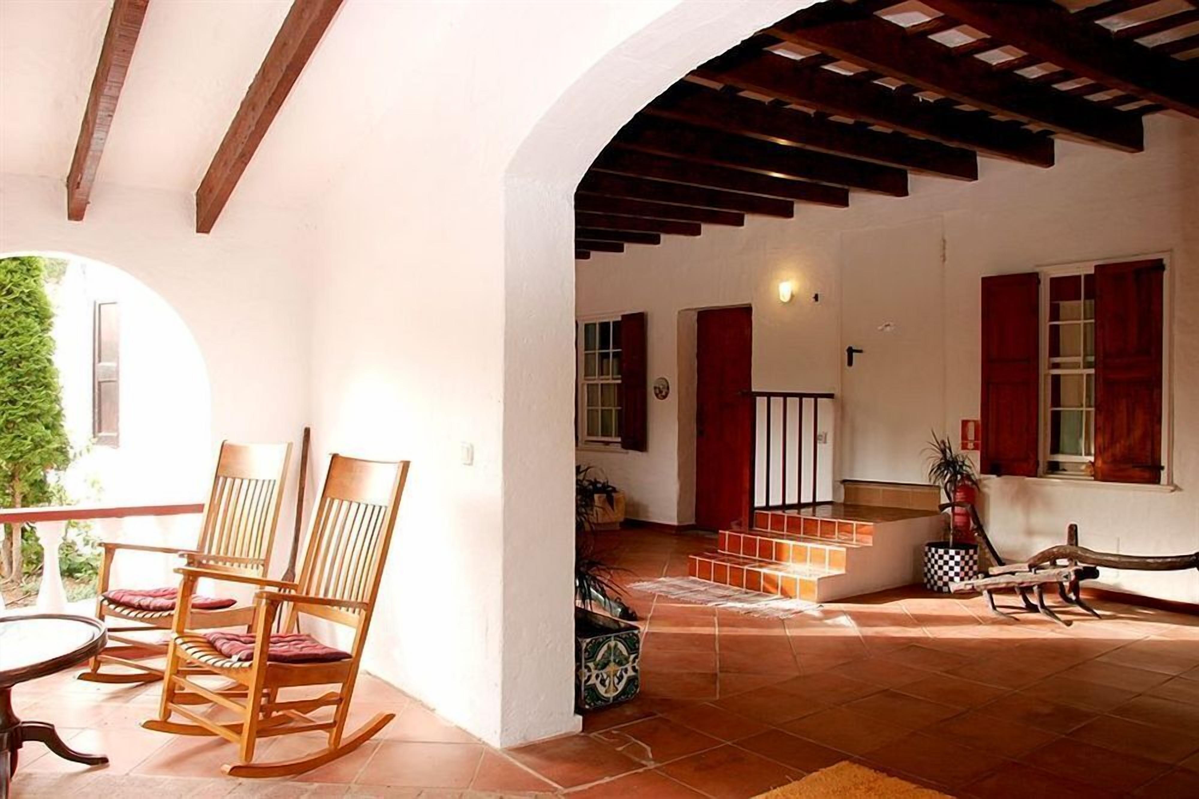 A spacious living area with wooden rocking chairs, a tiled floor, and a staircase leading to an upper level.