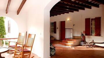 A spacious living area with wooden rocking chairs, a tiled floor, and a staircase leading to an upper level.