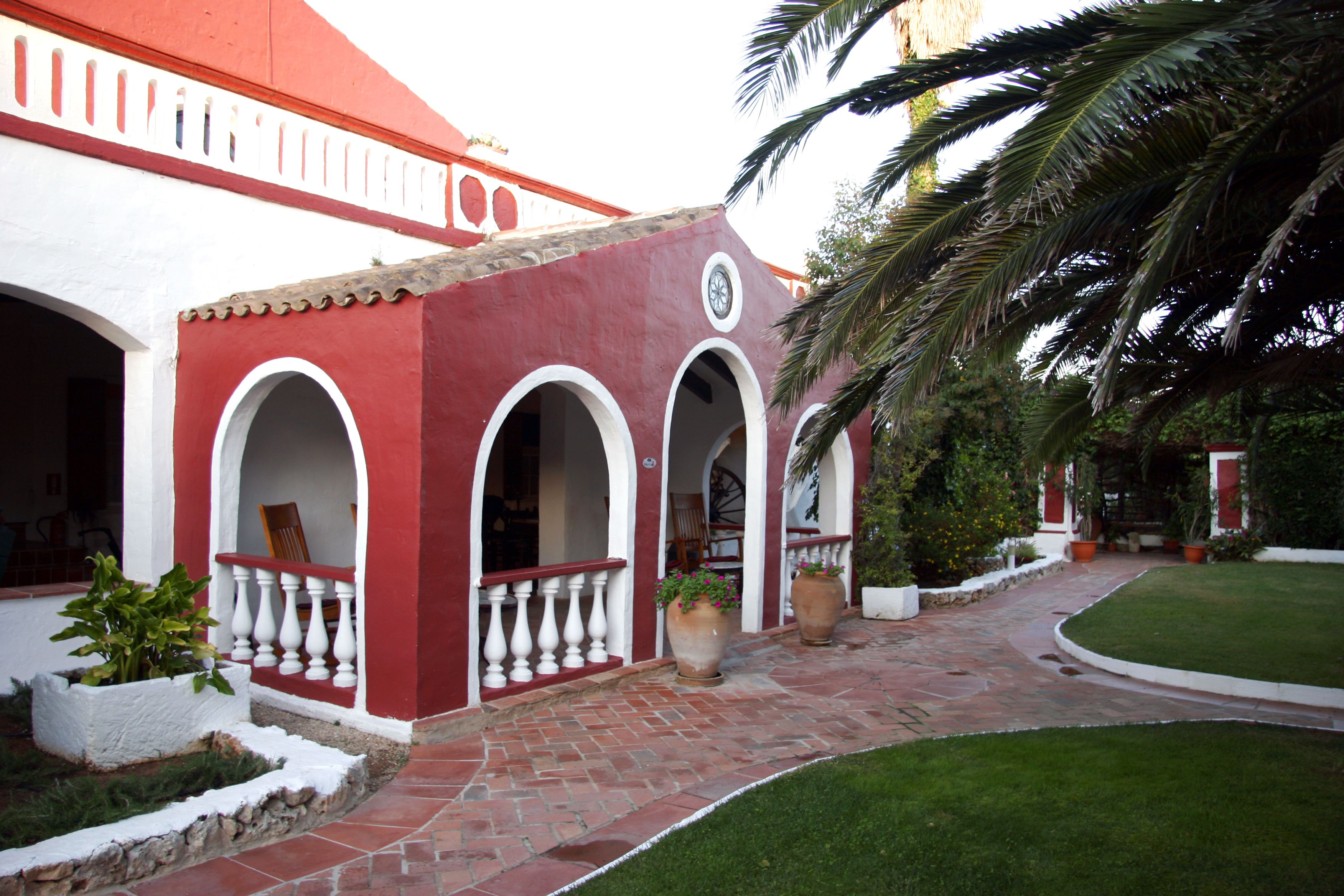 A courtyard with a red and white building, a paved walkway, and potted plants.