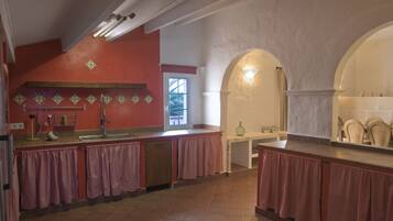 Una cocina con pared roja, un lavamanos y una ventana.