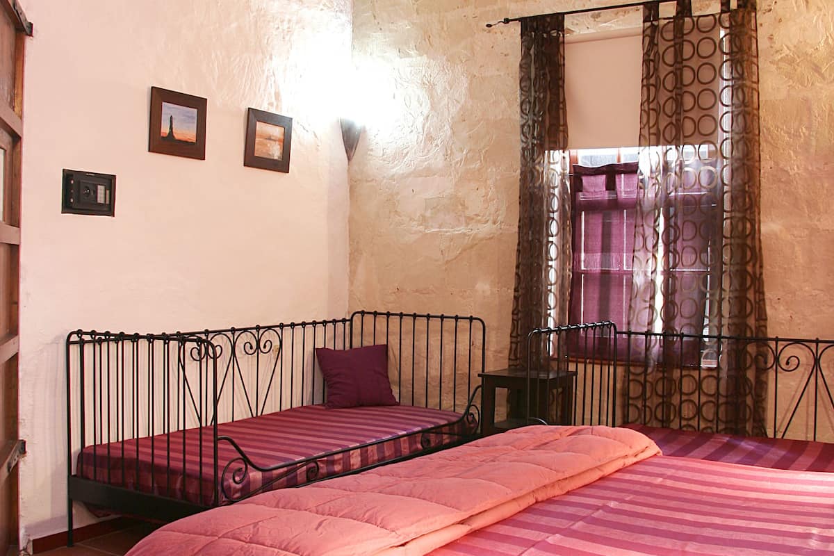 A room with a bed, a small table, and a window with curtains.