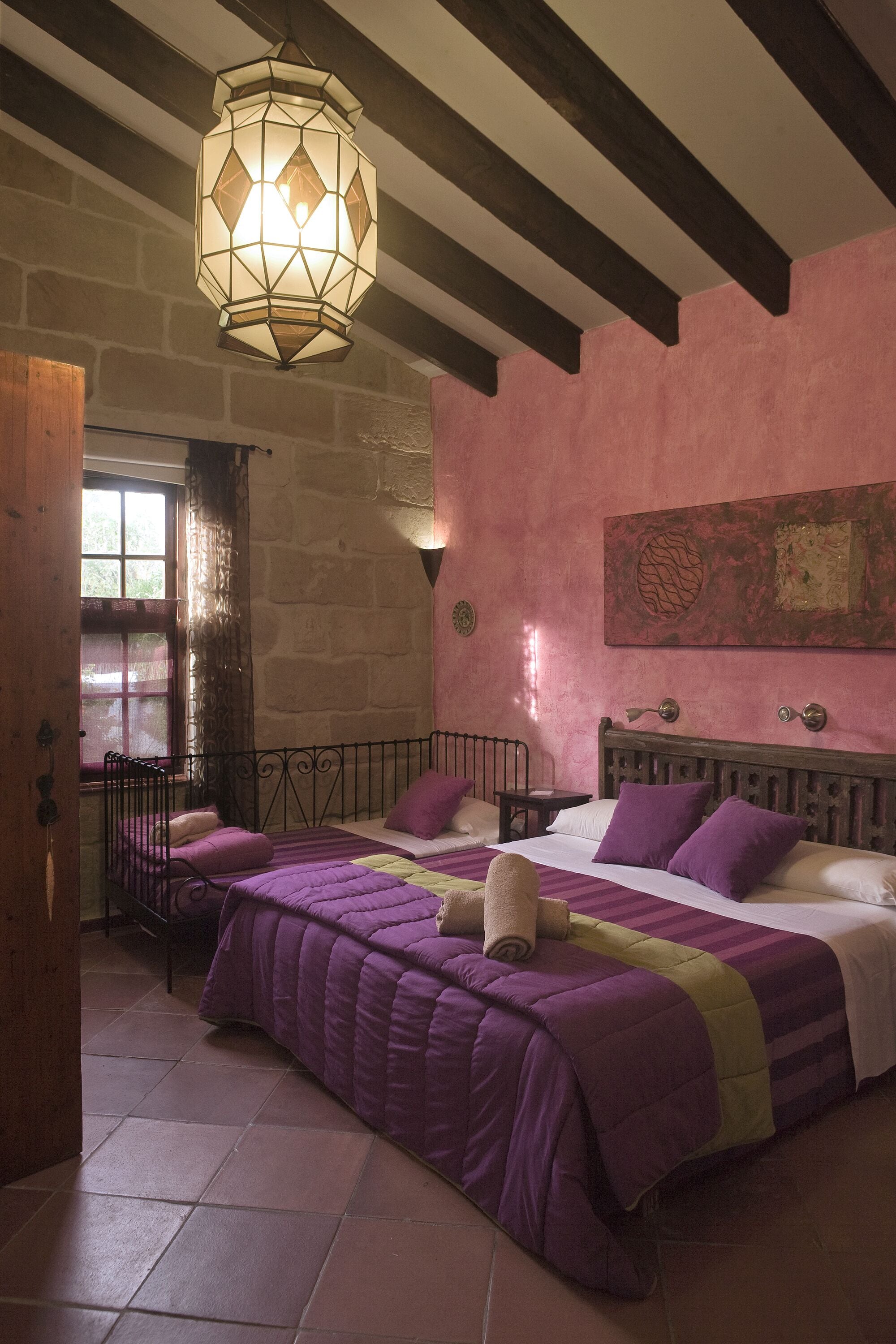 Une chambre avec deux lits, une grande fenêtre et un luminaire décoratif.