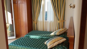 Una habitación con cama, armario de madera y una pequeña mesa.