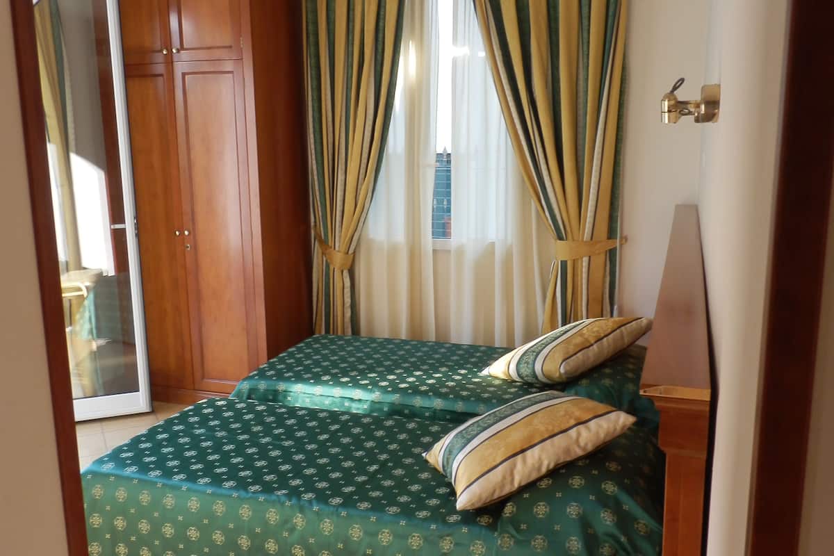 A room with a bed, wooden wardrobe, and a small table.