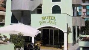 Un hotel de varios pisos con fachada verde claro, balcones en cada planta y un letrero que dice "HOTEL Your House".