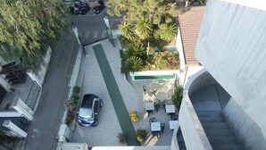 Una terraza en la azotea con mobiliario exterior y un coche estacionado en la entrada.
