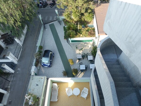 Terraço no telhado com área de estar externa e um carro estacionado na entrada.