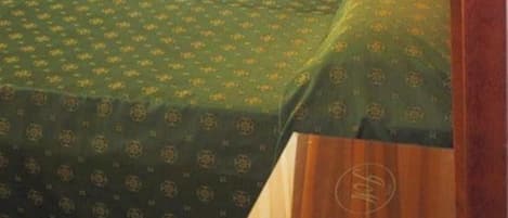A bed with a green patterned bedspread and a wooden headboard.